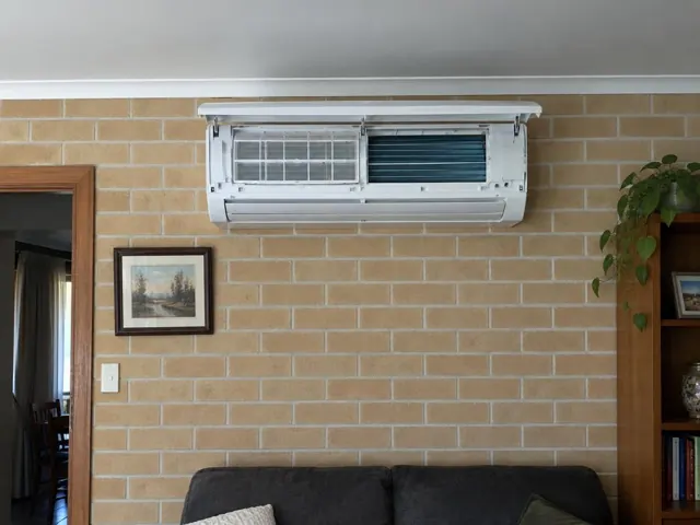 Clean open split system on a brick brick wall above a sofa in a home interior in Klemzig