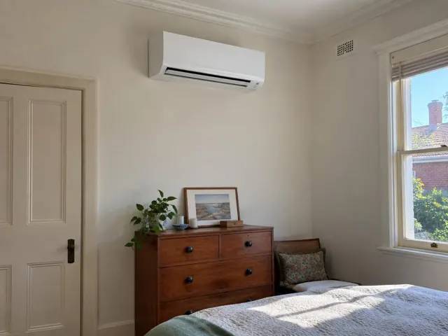 White split system on a cream wall above a timber dresser in a bedroom with a window in Prospect